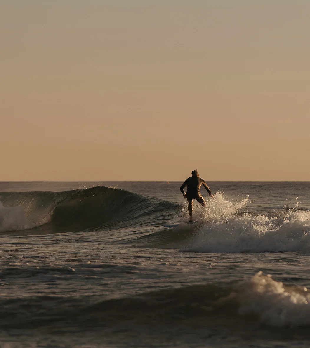 A lone surfer trimming along a small evening wave off the Palm Beaches.